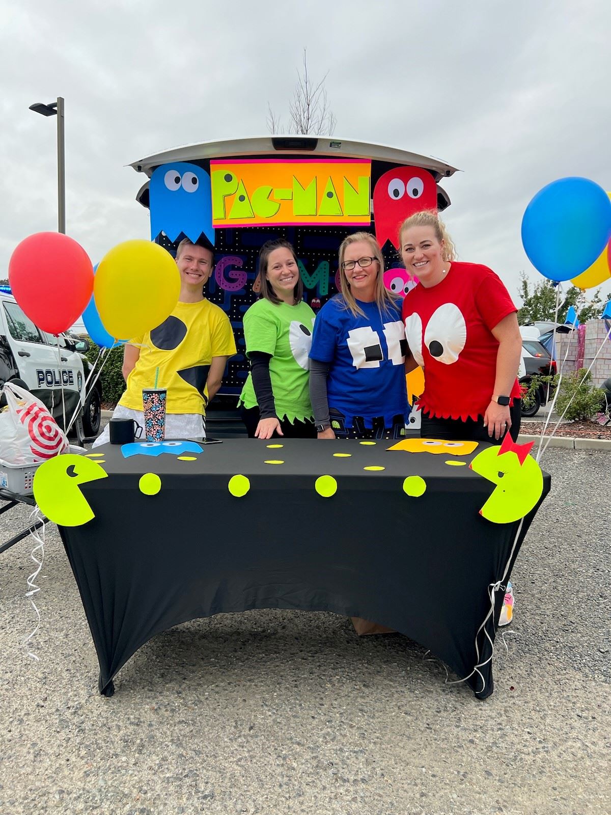 Four people pose behind a table dressed as Pac-Man characters.